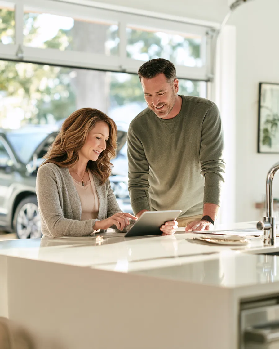 Couple in their 40s at a kitchen island reviewing a car repair estimate on a tablet with the Auto Approve calculator.